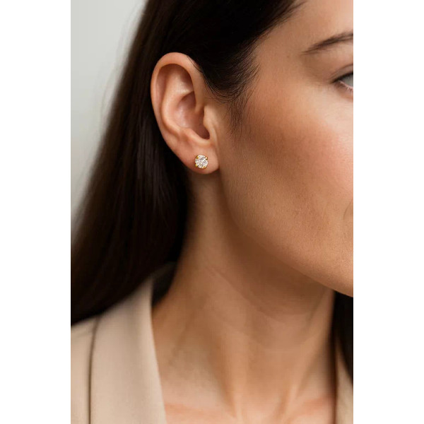 Femme portant une boucle d'oreille clou en or jaune 18 carats sertie d’un oxyde de zirconium rond