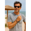Homme d’une quarantaine d’années en t-shirt gris portant le bracelet rouge Gambier à trois perles de Tahiti, en bord de mer.