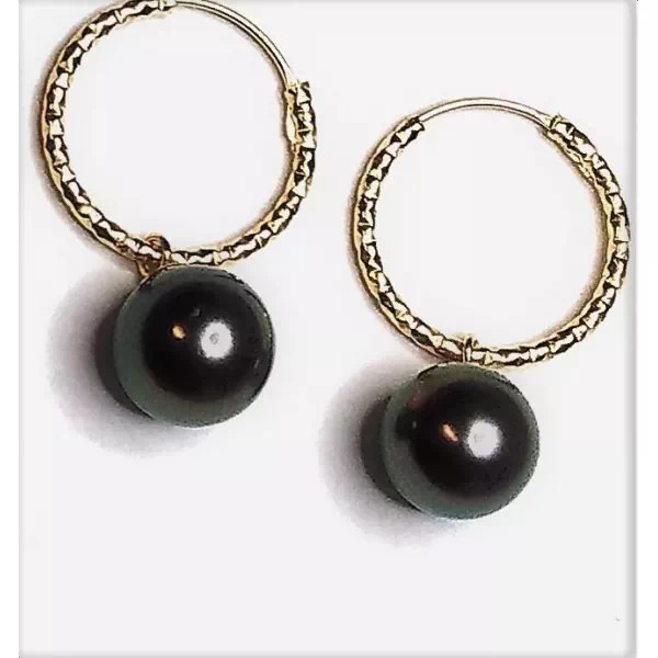Vue rapprochée des boucles d’oreilles créoles Joyce en or 18 carats et perles de Tahiti rondes.