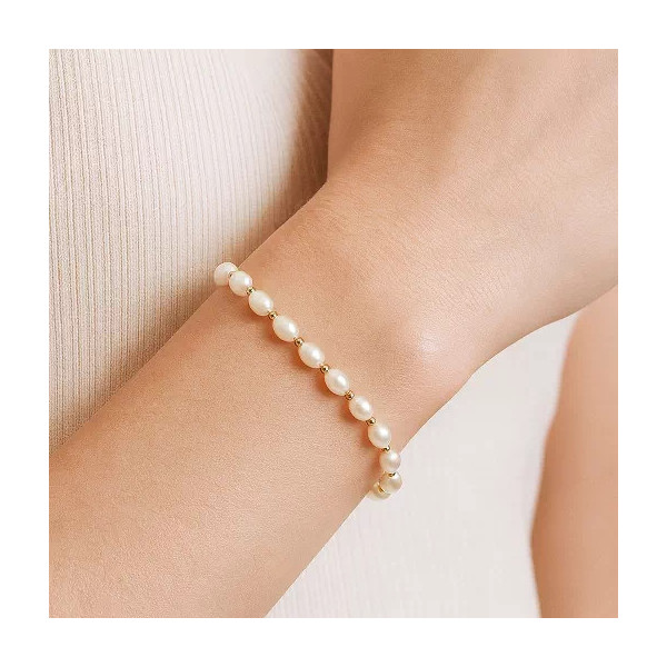 Bracelet Anaïs porté au poignet d’une femme – perles d’eau douce blanches et perles intercalaires en or jaune 18K
