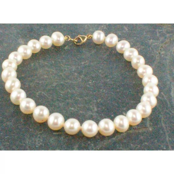 Aurore bracelet with round white freshwater pearls displayed on a dark marble background