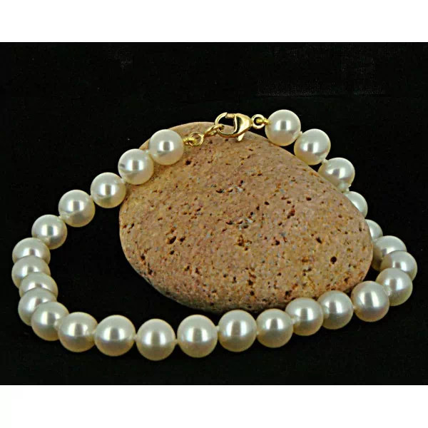 Bracelet Aurore en perles de culture blanches posé sur une pierre – fermoir en or jaune visible