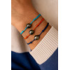 Trois bracelets en coton coloré et perles de Tahiti cerclées portés au poignet d’un homme