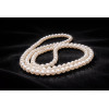 Sautoir de perles d’eau douce Sophia posé sur fond sombre, perles blanches brillantes