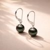 Boucles d’oreilles dormeuses en argent 925 avec perles de Tahiti rondes posées sur surface claire, lumière naturelle