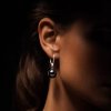 Sterling silver 925 earring with round Tahitian pearl worn on ear, close-up view, dark pearl with green overtones
