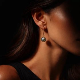 18k yellow gold earring with 8 mm round Tahitian pearl worn on the ear, side view with studio lighting